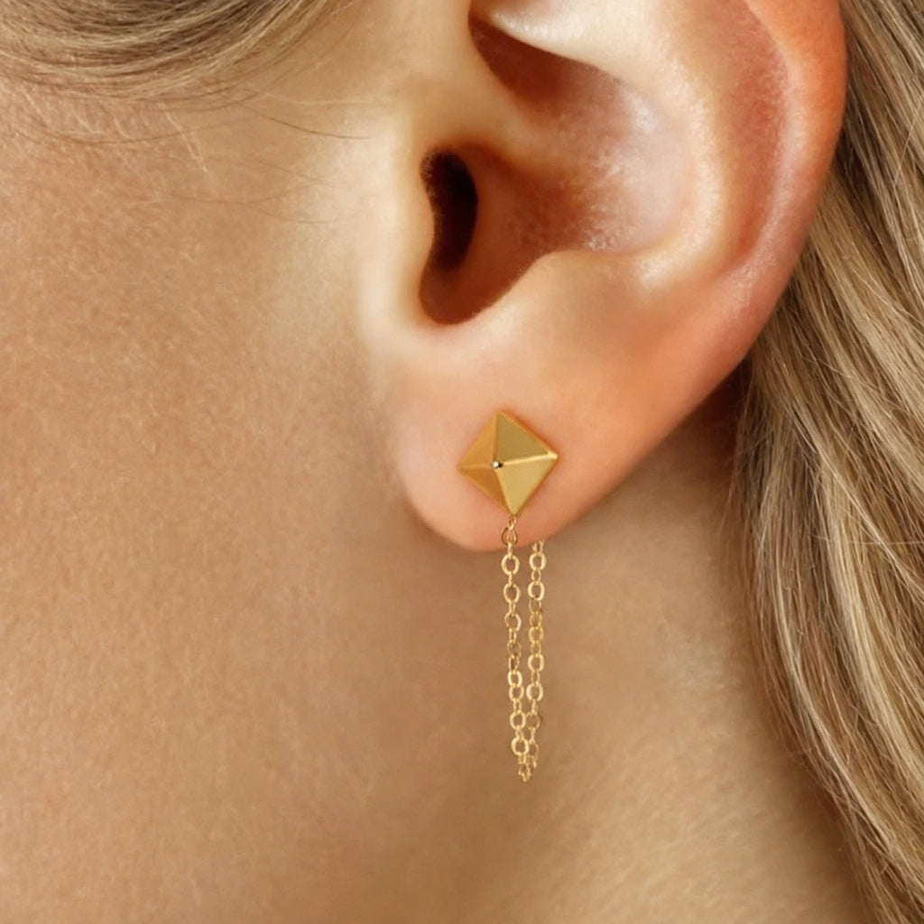14k yellow gold pyramid stud chain earring worn on the ear, with a faceted stud and delicate chain loop below the lobe.
