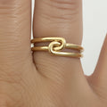 14k solid gold knot double ring - sculptural infinity knot double band, yellow gold closeup on model hand
